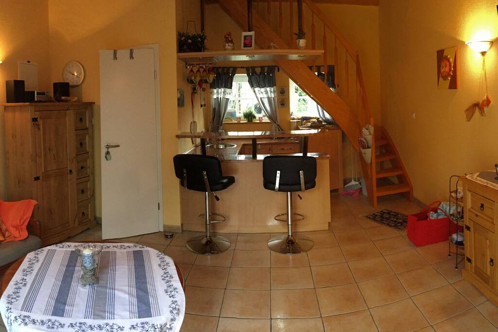 Wohnbereich mit offener Küche und Zugang zum Bad sowie Treppe zum Schlafbereich