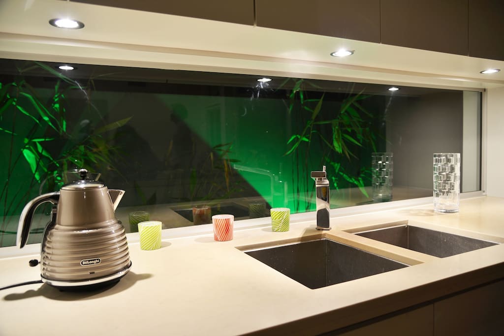 Glass splashback in kitchen with green lights outside