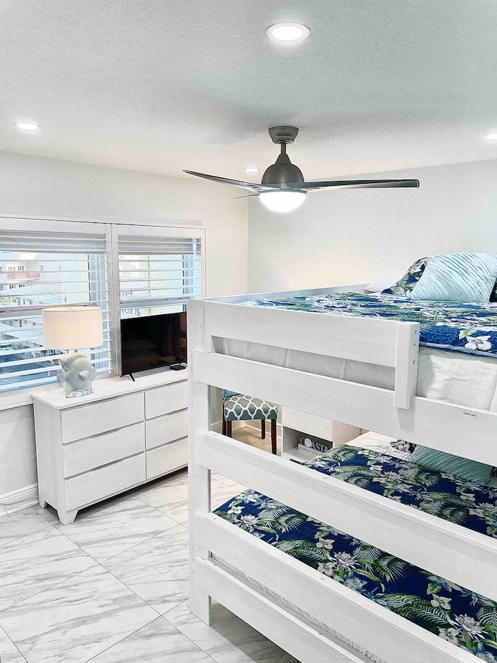 Dormitorio para huéspedes con literas tamaño queen, TV, cómoda y mesita de noche.