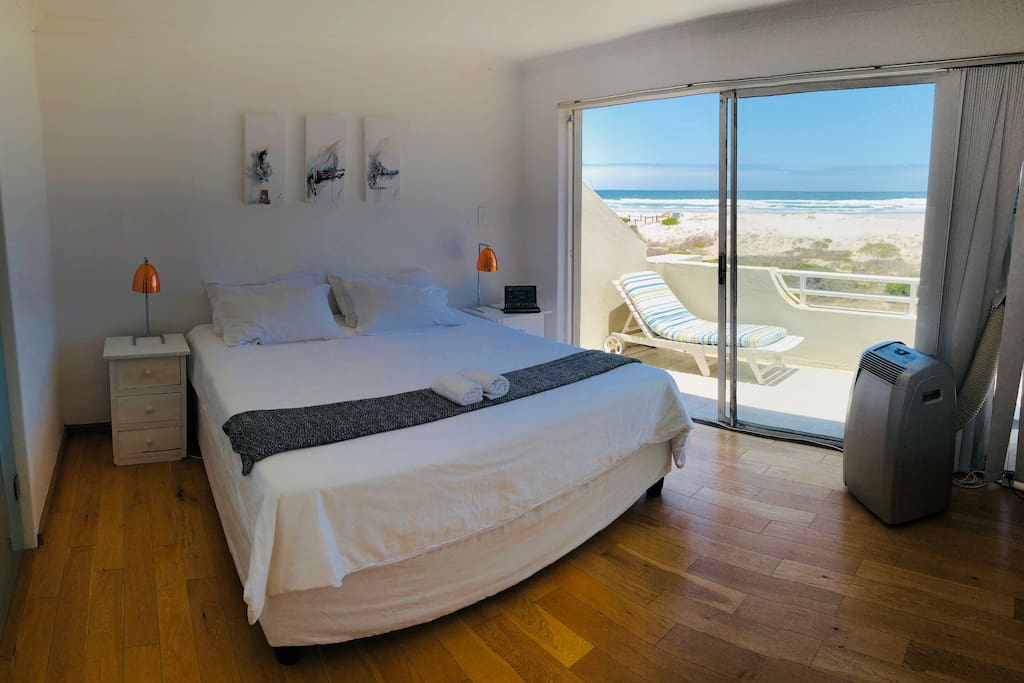 The main bedroom has a beautiful view of the ocean, and features a King Extra Size bed with white linen, and an on-suite bathroom.