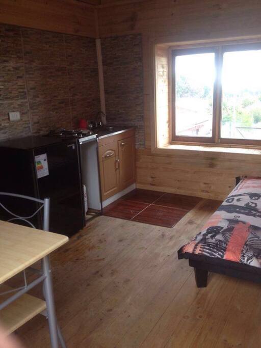 Area de cocina equipada y living con vista al bosque