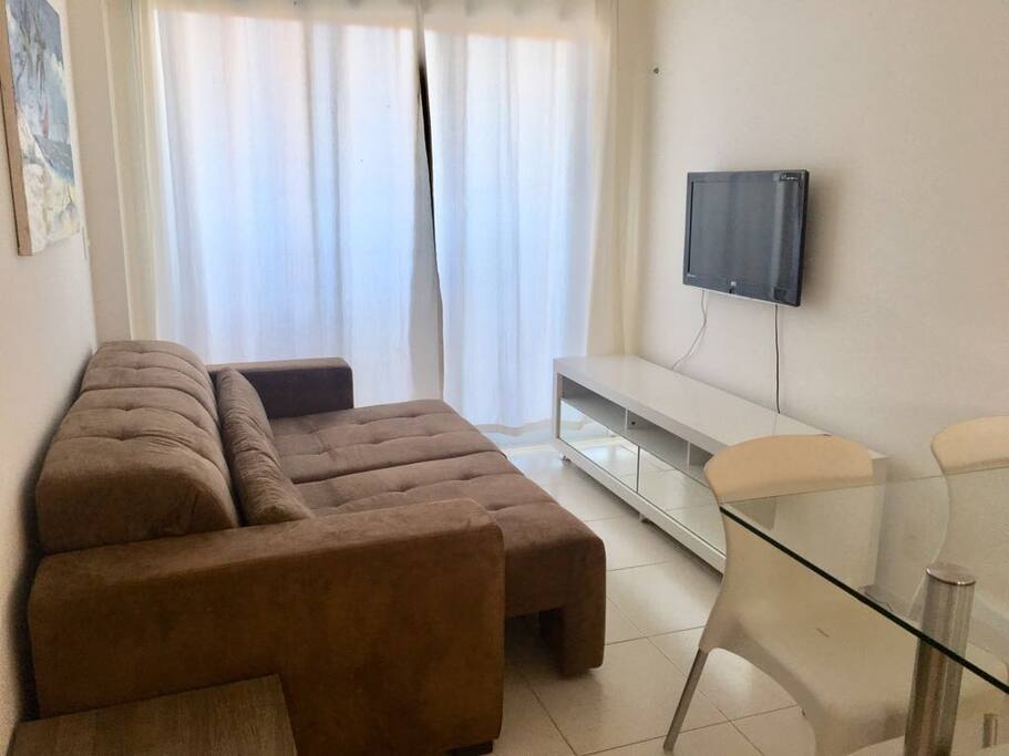 Sala equipada com sofa retratil, ar condicionado split, tv, mesa com 4 cadeiras
