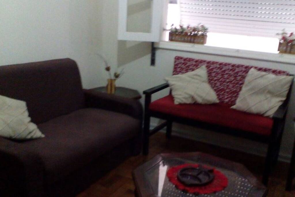 sala,com sofá-cama,sofá dois lugares, poltronas,tv,mesa, 4 cadeira, armário bar e ventilador de teto .