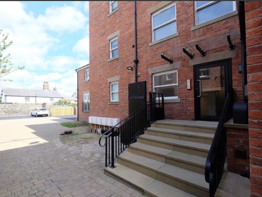 The rear car park with the apartment entrance. At the back of the car park is also a side gate taking you even closer into the centre of town. One space is allocated to the apartment.