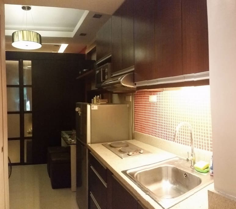 kitchen has utensils, microwave oven, refrigerator and stove