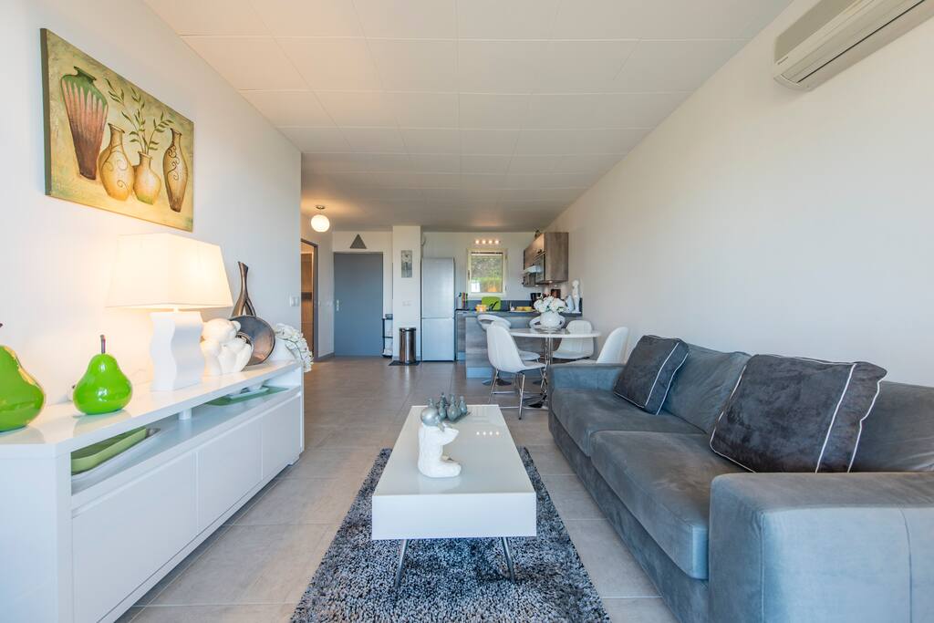 coin télévision ouvert sur cuisine et terrasse vue Mer