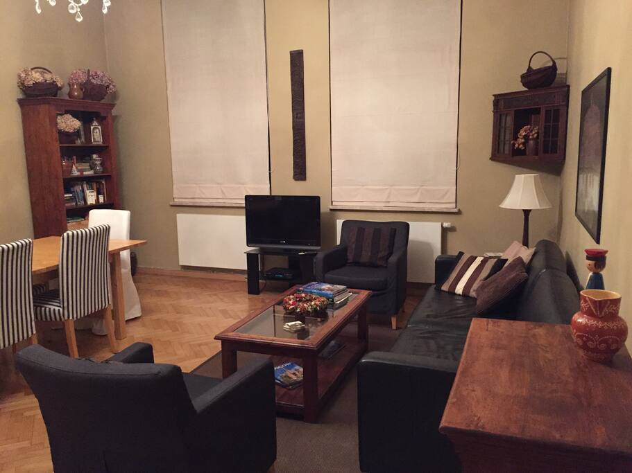 Living/dining room with luxury sofa bed, Roman shades and solid wood furniture.