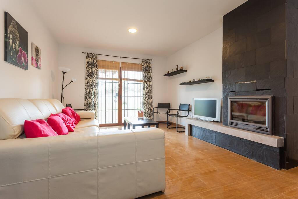 Salón con chimenea de diseño y amplio ventanal que conecta con la zona exterior.