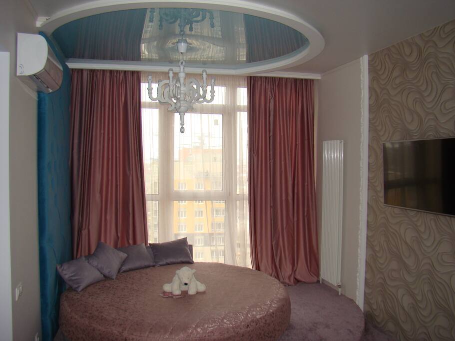 Living room with comfortable round double-size bed, flat-screen TV and air-conditioning