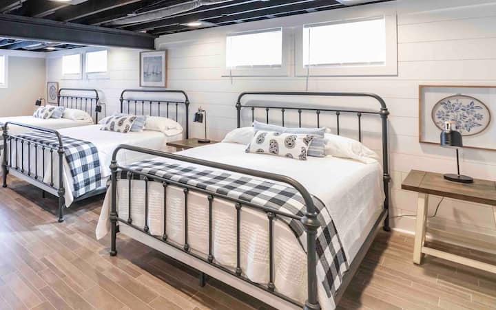 Lower level bunk room with three queen beds, a full bathroom with tub/shower combo, and another bedroom with one queen bed