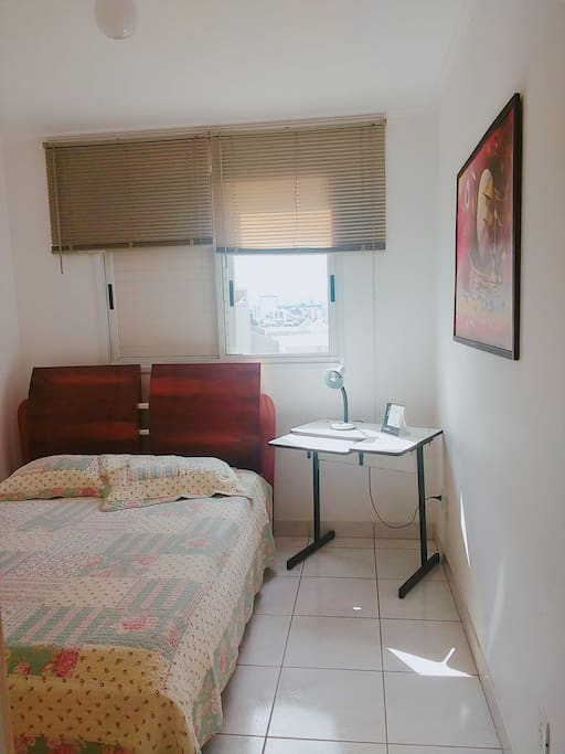 Quarto duplo com cama de casal, com escrivaninha, luminária e guarda-roupas. Double room w\ double bed, side table, lamp and closet.