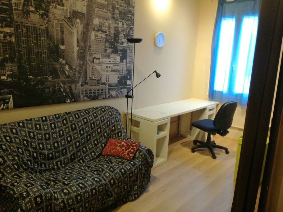 Habitación grande con sofá y mesa para ordenador.