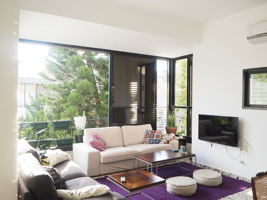 The living room is full with natural sunlight and green view