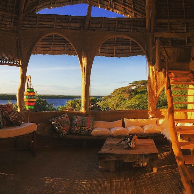 Lounge area with stairs going up to a double loft room. Windows looking out over 180 degrees views of creek and little beach 90feet below the house. Inside lantern made from beach rubbish. Palm weave matting is all locally hand made.