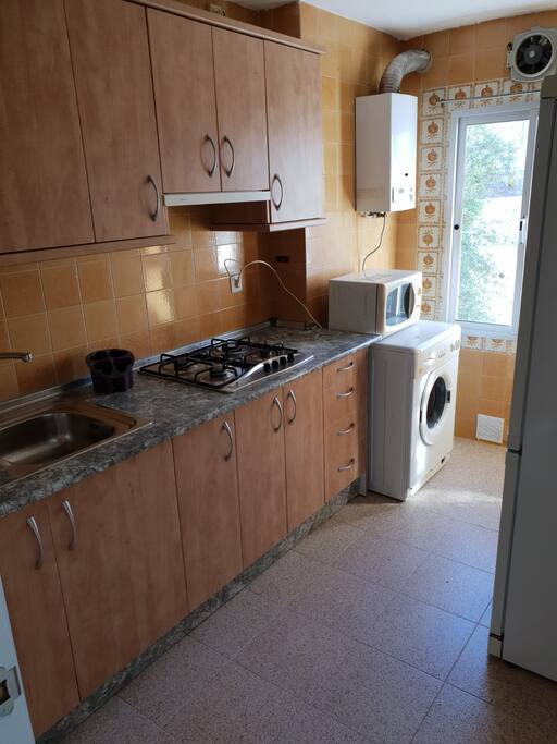 cocina equipada con lavadora, nevera y microondas