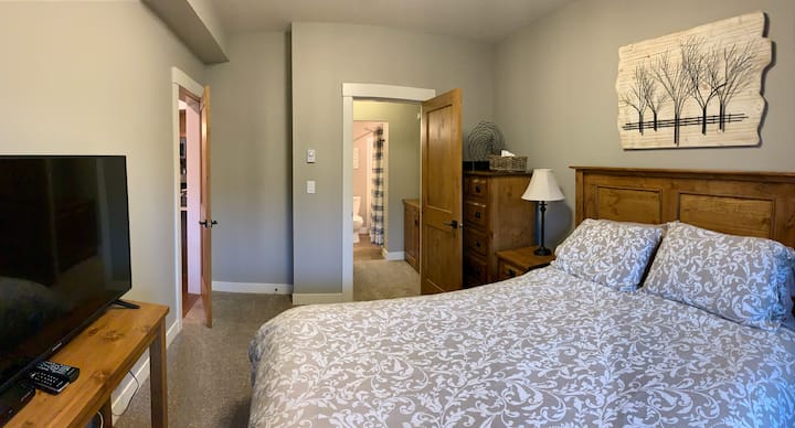 غرفة نوم رئيسية بسرير بحجم كبير وحمام داخلي وخزانة ملابس وتلفزيون 