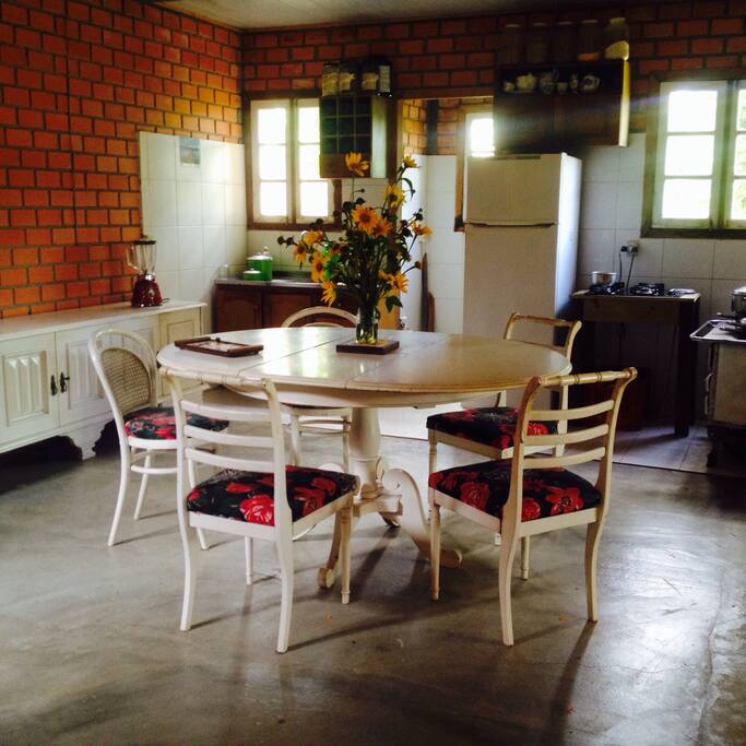 Sala de jantar e refeições integrada a cozinha com cook top e fogão a lenha