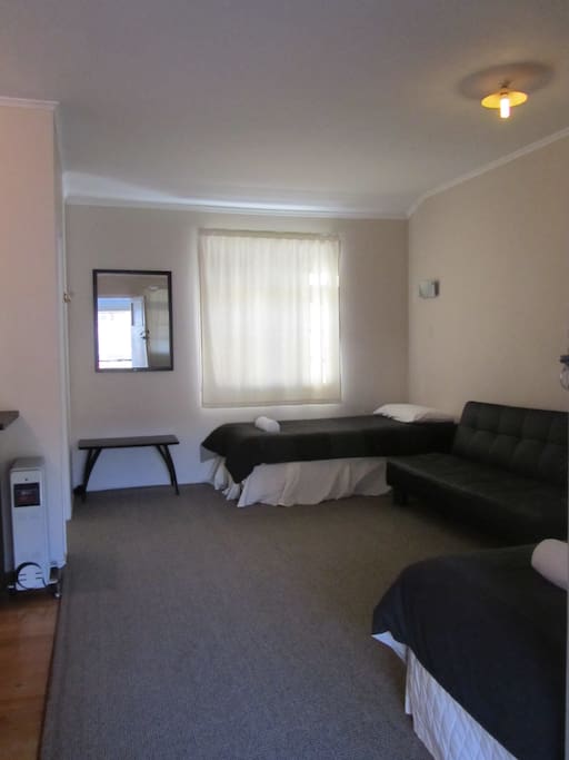 General studio set up, two singles and a queen bed, sofa and table. Linen and blankets supplied (image for illustration purposes and may vary slightly).