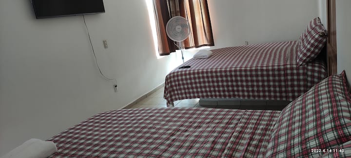 تحتوي غرفة النوم 1 على سريرين كبيرين ومروحة وتلفزيون.