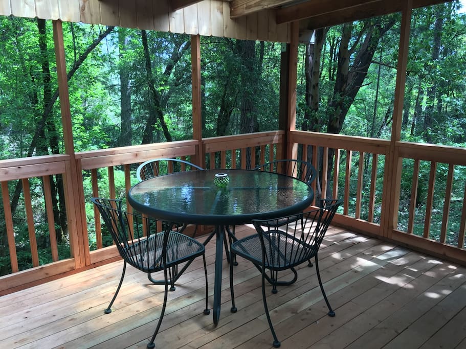 The renovated screened-in deck on the front porch of the cabin, overlooking the creek