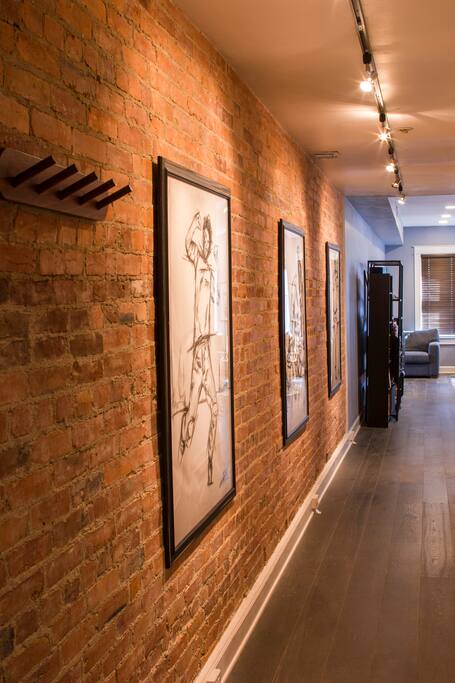 Long hallway with exposed brick and original artwork.