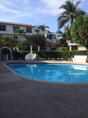 A private pool is surrounded by lush greenery and well-maintained landscaping. Sun loungers and a seating area are visible nearby, providing a comfortable space for relaxation. The tranquil waters of the pool reflect the clear sky, inviting guests to unwind in a serene environment.