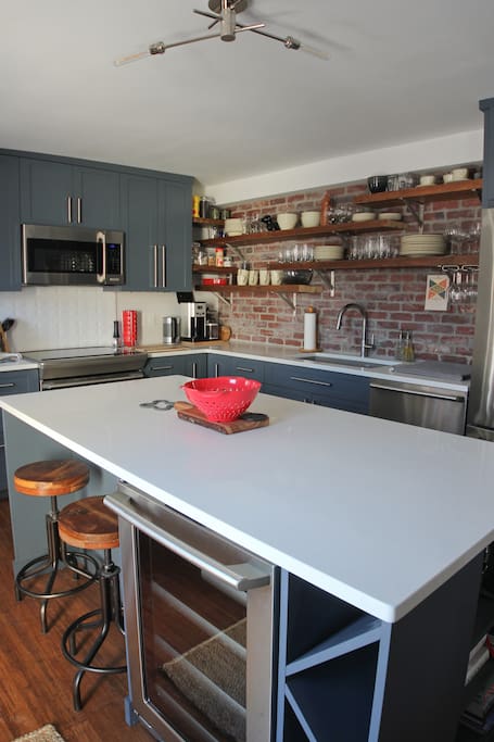 large central island in the kitchen with two bar stools and wine fridge