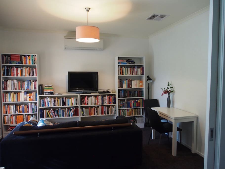 Guest lounge room with library, couch, tv/dvds, microwave, bar fridge, tea/coffee facilities, and console breakfast table.