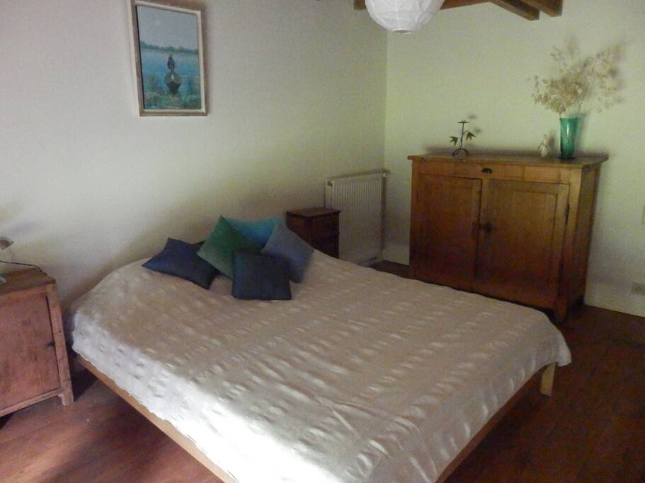 la chambre avec poutres apparentes, un lit king size et une jolie vue sur la terrasse et le verger. La chambre dispose d'un petit bureau avec accès wifi.