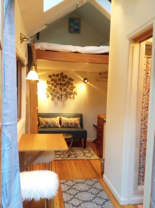 View from front door; collapsible kitchen table/work area & bathroom to right and loft up top.