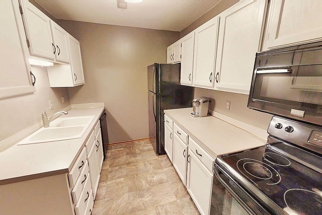 White kitchen with dishwasher, disposal, range/oven, microwave oven, and refrigerator with ice maker