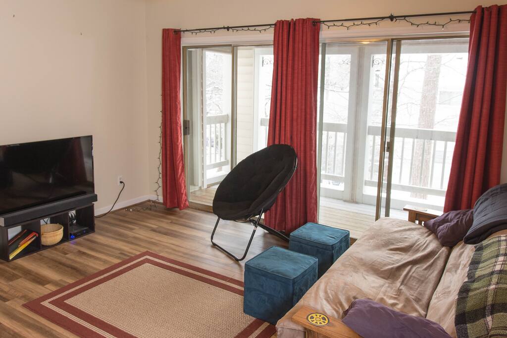 The living room has a chair, large futon, dual ottomans, and 45" TV hooked up to a computer for Netflix or any other media needs.