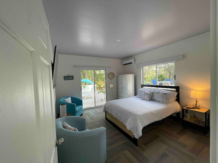 Grande chambre principale, avec lit queen, lit superposé avec lampe, deux fauteuils, placards, table basse, miroir, télévision écran plat avec Netflix et avec vue sur la piscine