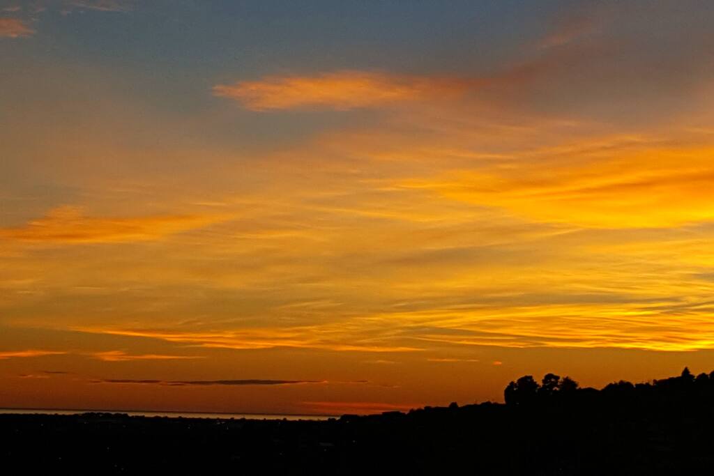 Breakfast in the guest lounge with the sky over the city, a blaze of colour.....the sea in the distance....