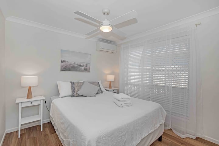 غرفة نوم تضم سرير كوين مع سرير مريح وبياضات عالية الجودة ومكيف هواء ودورة عكسية ومروحة سقف لراحتك. 