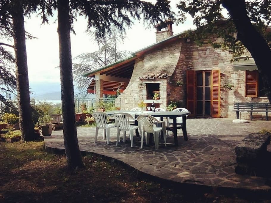 spazio esterno attrezzato con tavolo, camino in muratura per mangiare e riposarsi con vista diretta sul lago.