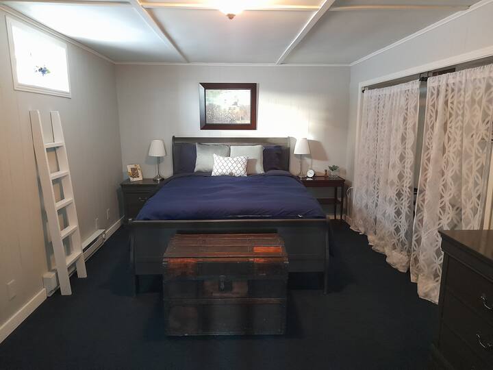 Bedroom with comfy Queen bed, dresser, hanging rack, luggage stand, window, alarm clock, linens , pillows and bedding included.