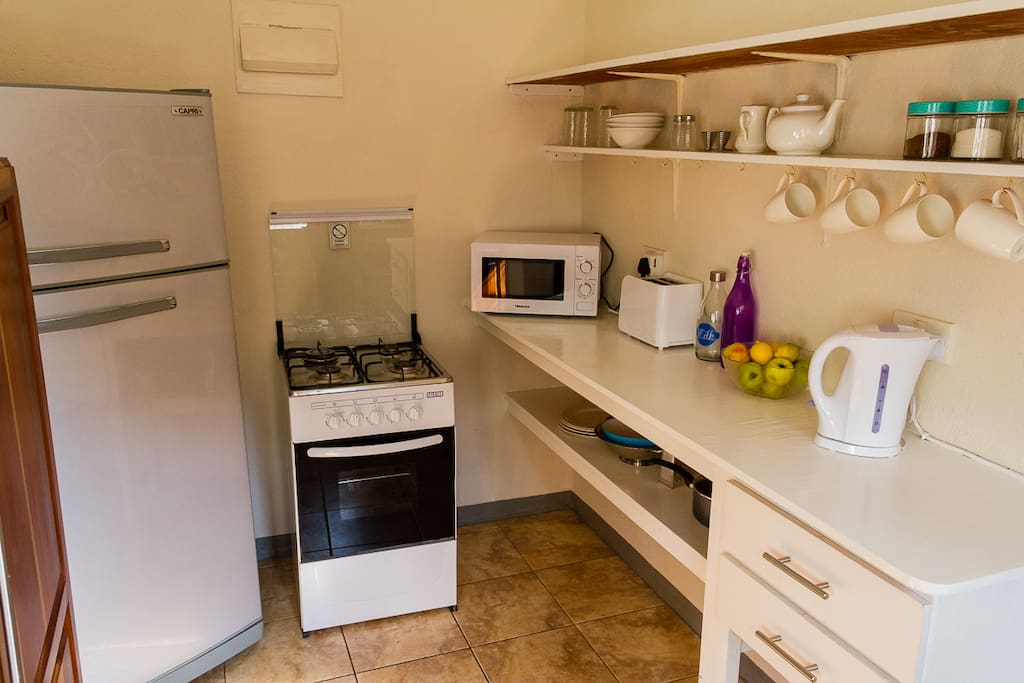 Kitchen with fridge, gas stove, microwave, toaster and kettle.