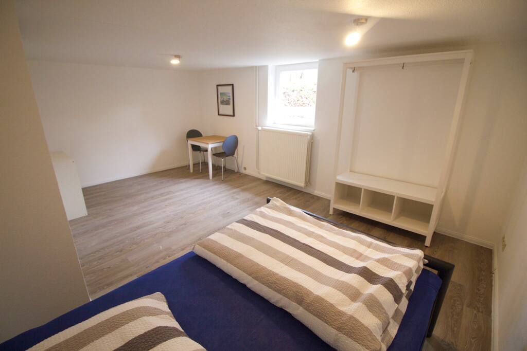 Zimmer mit Doppelbett, Tisch und Stühlen und Kleiderschrank