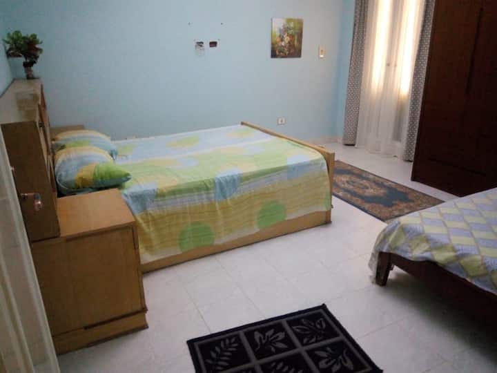 chumba chenye kitanda cha watu wawili na kitanda cha mtu mmoja