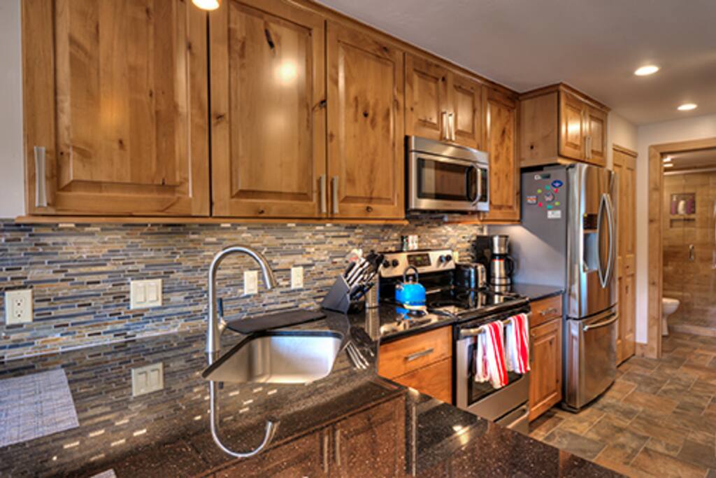 Brand new, modern and sleek kitchen, with bar stools for two at end.