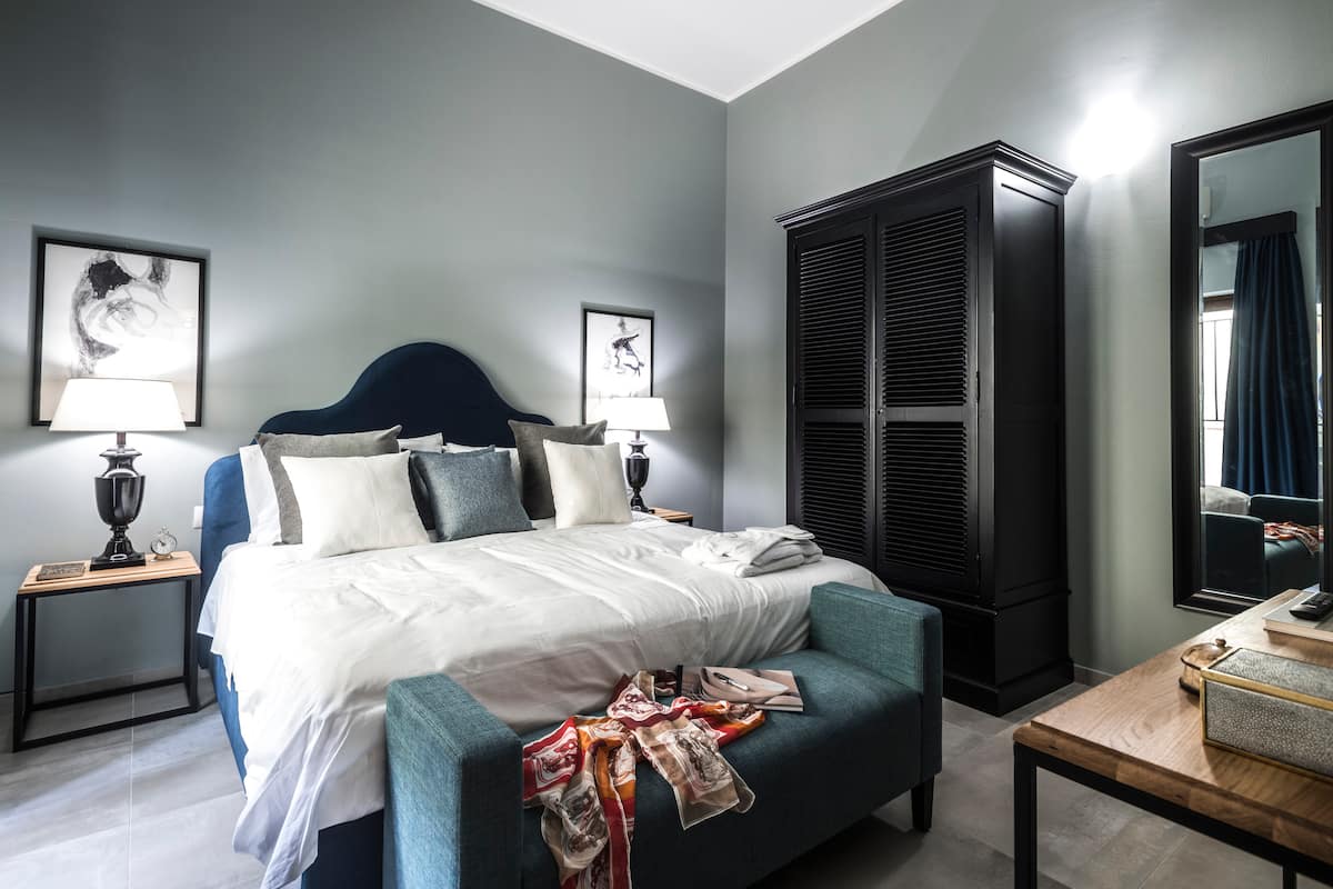 Camera da letto matrimoniale con testiera in velluto blu, armadio nero e disegni di Renato Guttuso