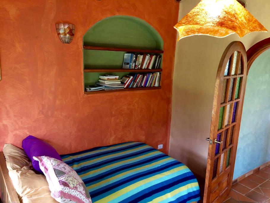 Guest room with a twin bed and growing library. The colored glass on the door and unique lamp are a nice touch.