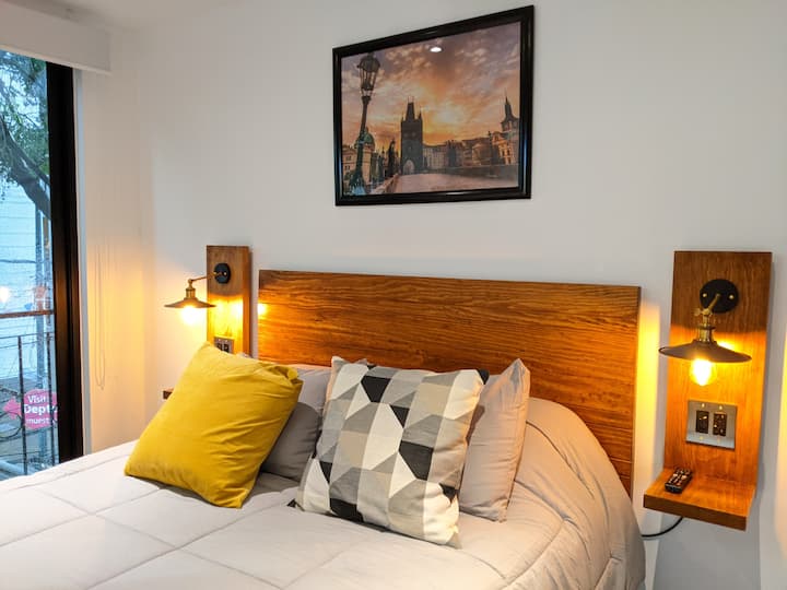 Dormitorio con cama tamaño queen, TV inteligente, Netflix, lámparas regulables junto a la cama, armario, apagones y vista a la calle.