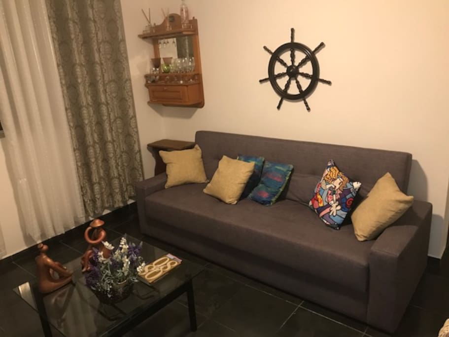 Sala com sofá cama casal e ventilador de teto e TV