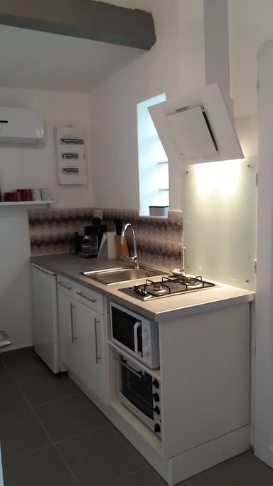 Cuisine équipée, avec four, micro-ondes, grille-pain, cafetière, bouilloire, frigo, ustensiles de cuisine, vaisselle.