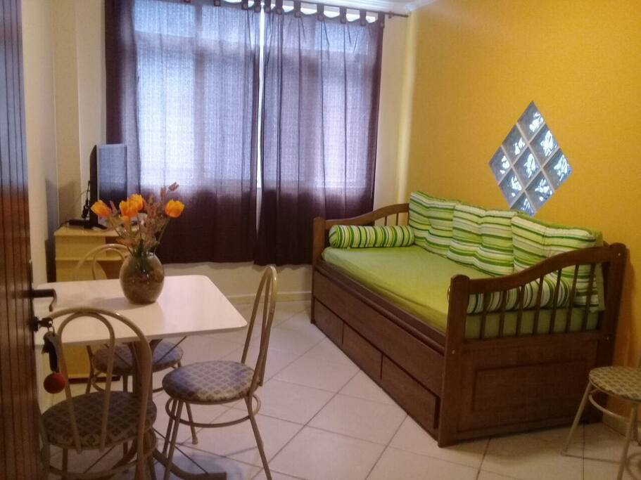 Sala com mesa, TV, Bicama/Sofá e ventilador de teto.