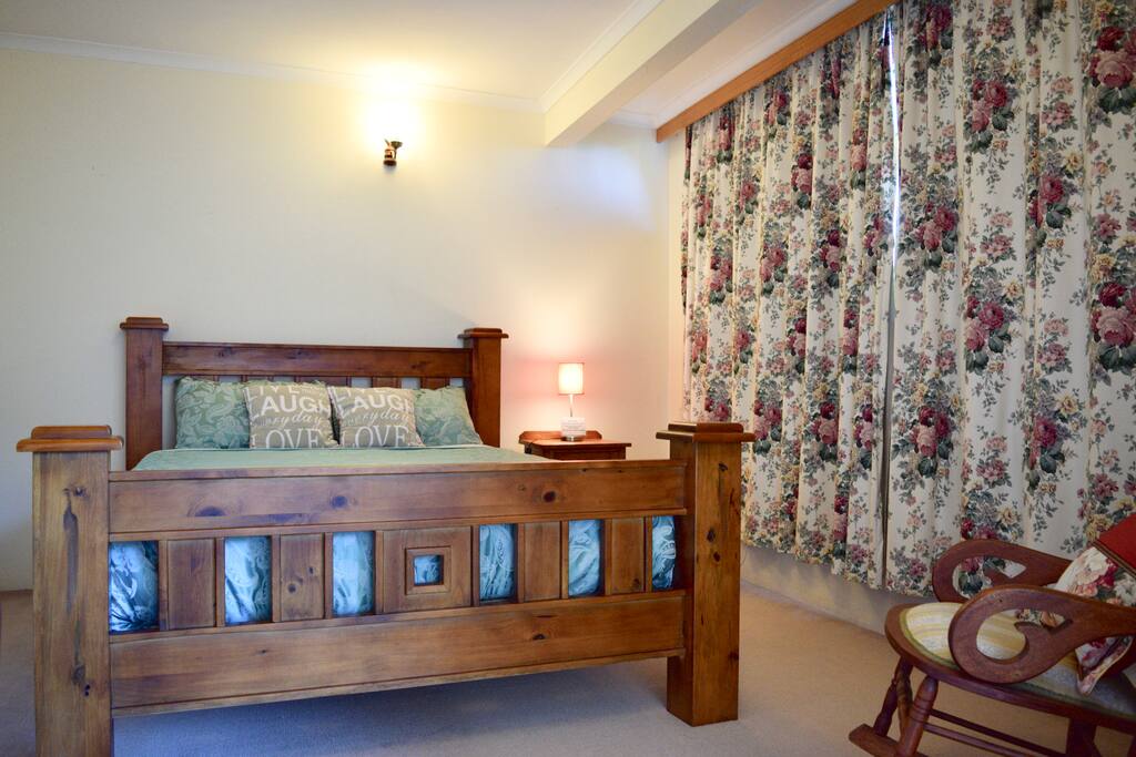 This large bedroom contains a queen-size bed. The other end of the room contains another space which can be used as a dressing room, a lounge or second bedroom.