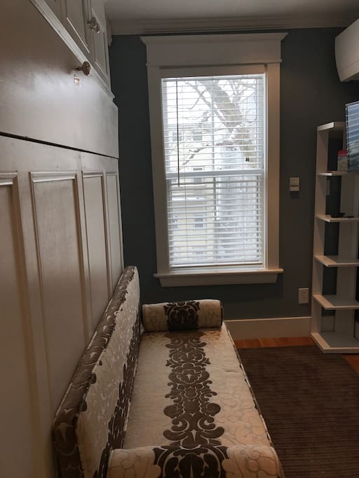 Murphy bed closed. Tiny but luxurious. Built-in storage shelves & extra down comforter to left of window. Adding a private entrance & balcony later in Fall!