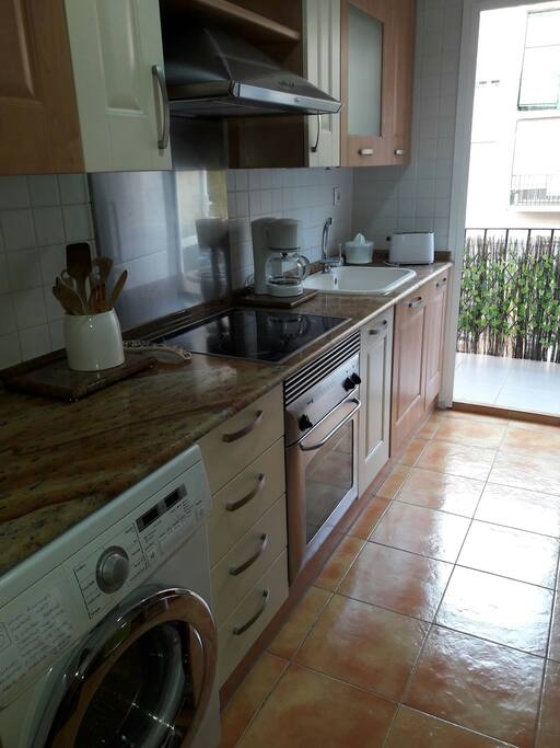 Cocina con vitrocerámica/ inducción y balcón al patio interior. Equipada también con lavadora, lavavajillas, nevera, microondas, tostadora, cafetera y zumera.
